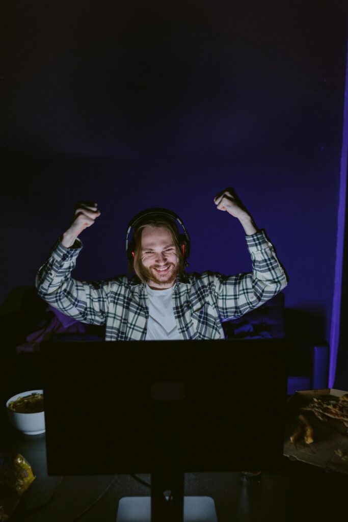 Home Man with headphones celebrates gaming victory, indoors and happy.
